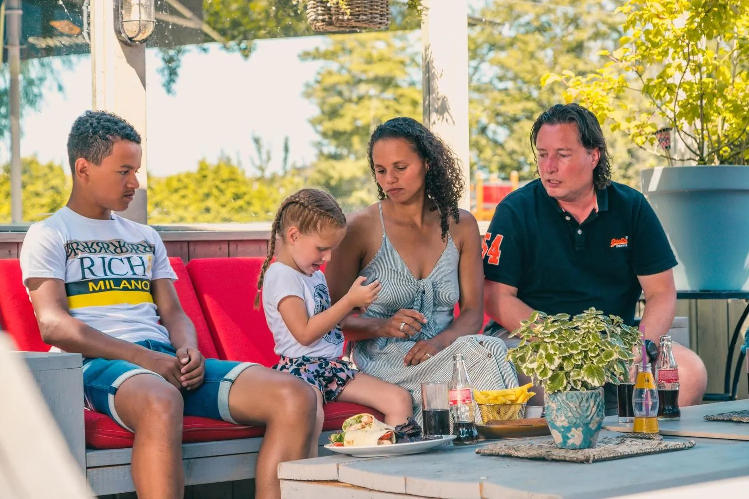 Gäste mit Parkbetreuer auf roter Terrassen-Lounge beim Entspannen