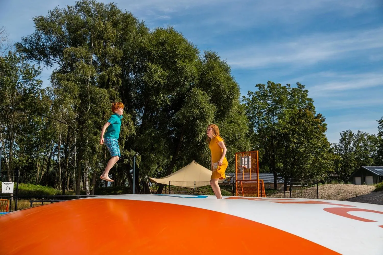 Trampolin im Freizeitbereich des Ferienparks, Bäume und Spielplatz sichtbar