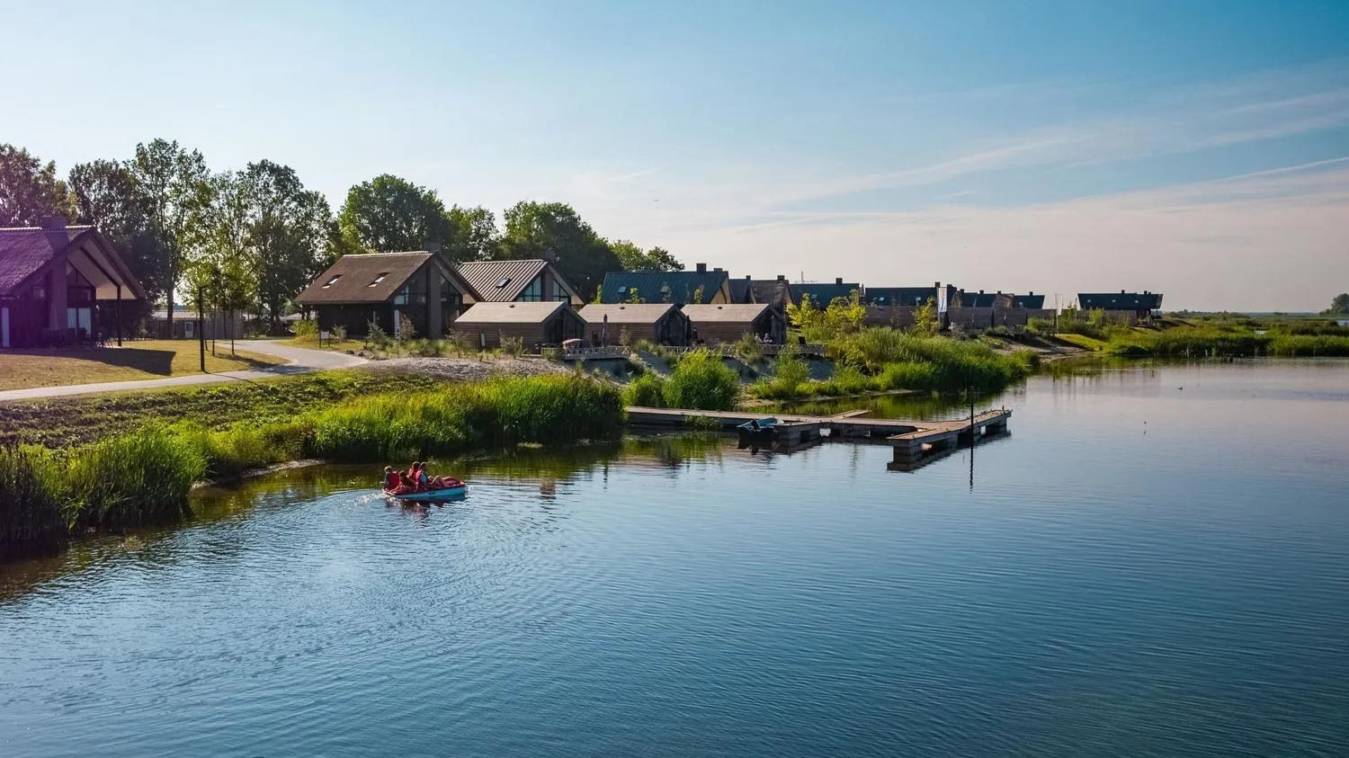 Ferienhäuser mit dunklen Dächern am See, Kajak im Wasser, Bootsanleger