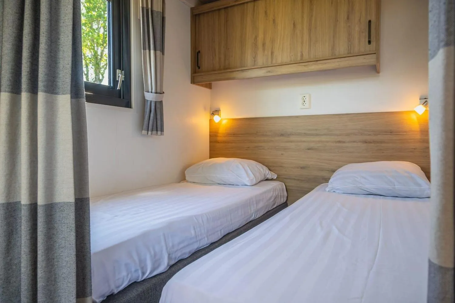 Modernes Schlafzimmer mit zwei Einzelbetten und indirekter Beleuchtung