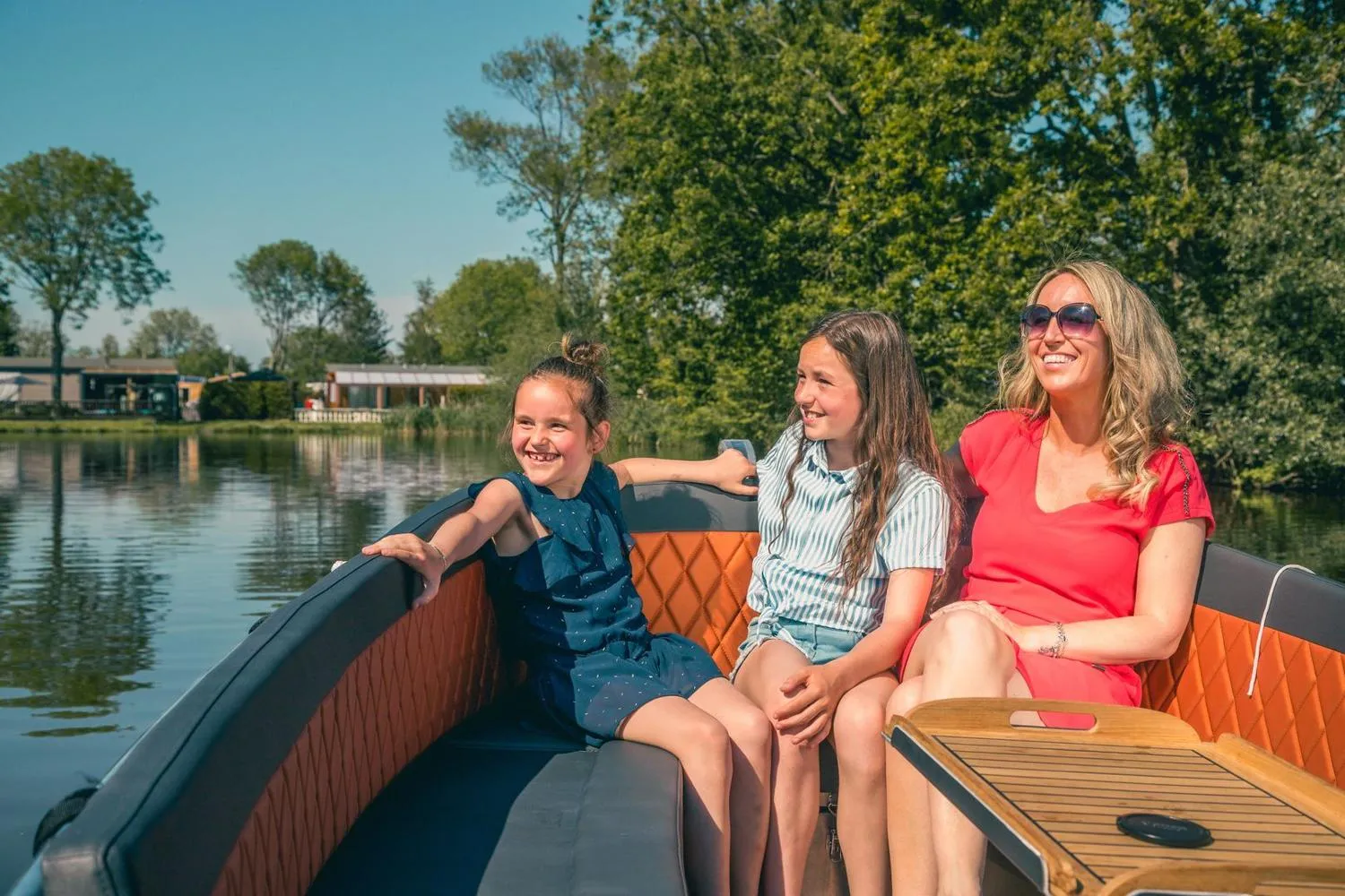 Familie sitzt lachend im Boot auf dem Parkwasser