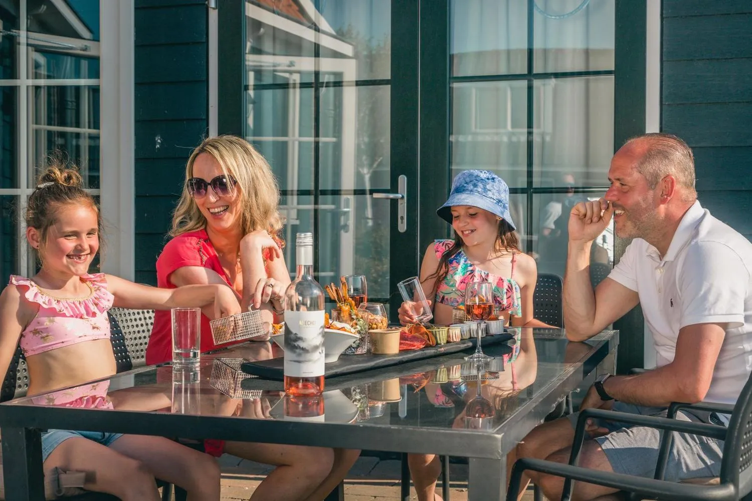 Familie sitzt beim Essen auf der Terrasse des Ferienhauses