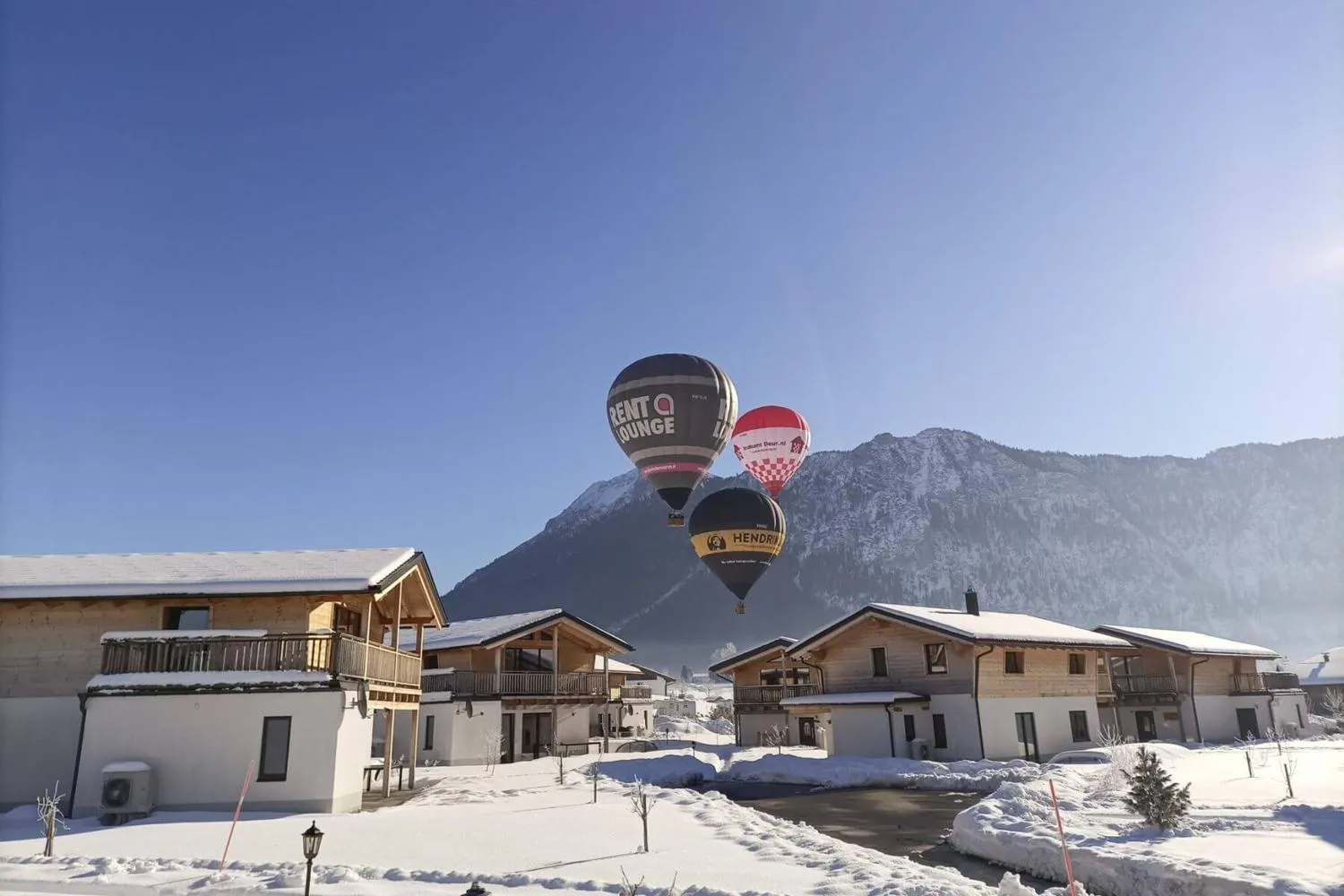Heißluftballons über Chalets und Bergen in Schneeumgebung
