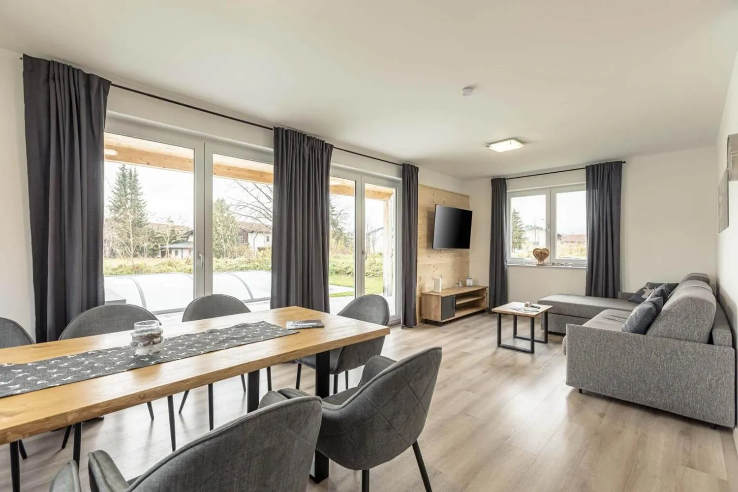 Großer Wohnbereich mit Esstisch, Sofa und großen Fenstern